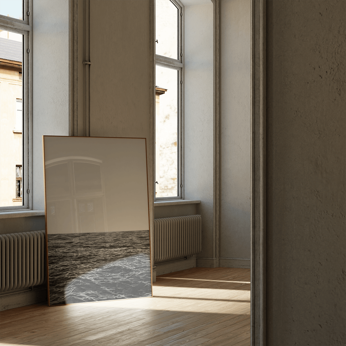 A large framed art print leaning against a window in a sunlit room with wood floors and cream walls.