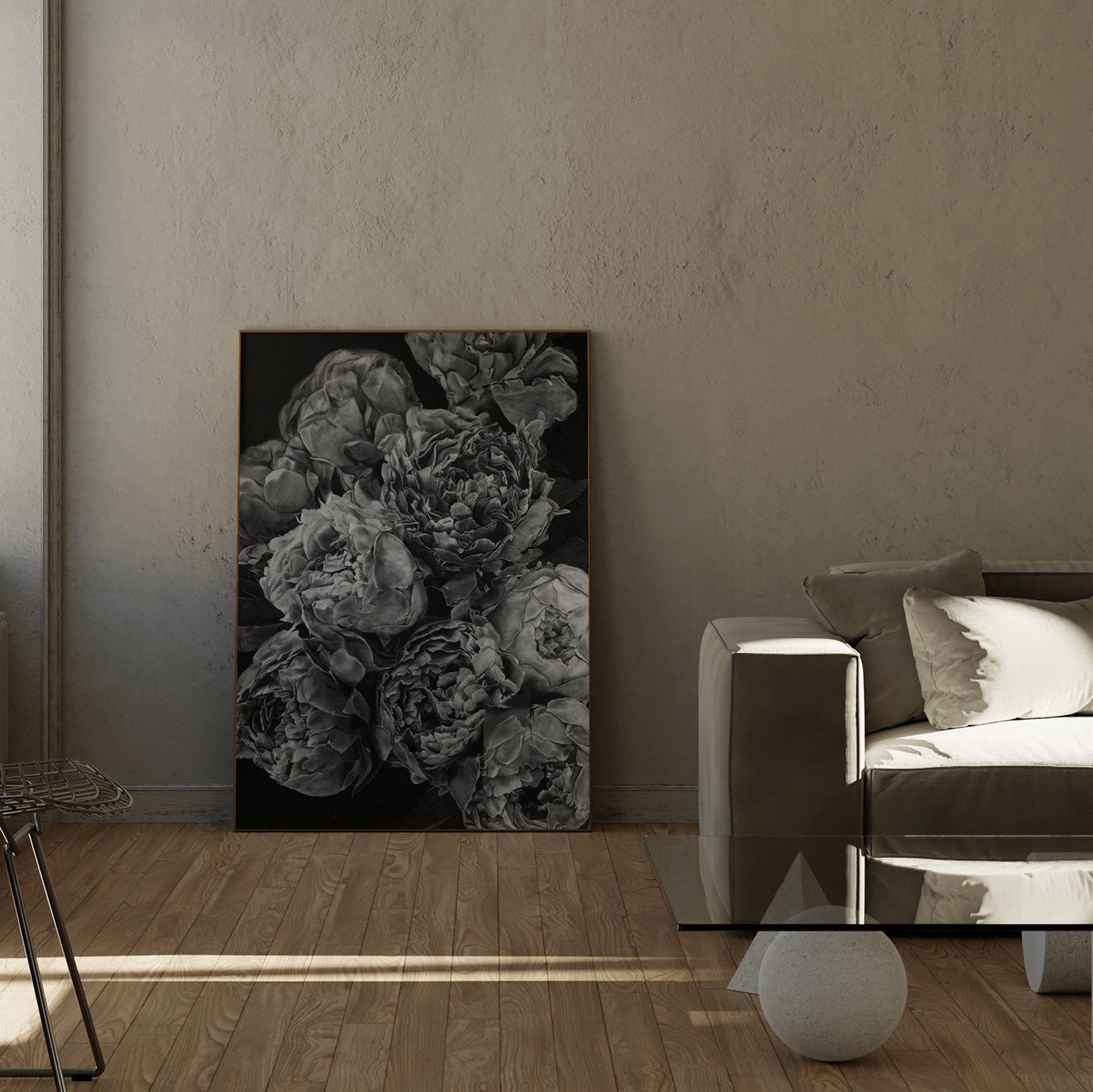 A vertical black and white floral art print depicting peonies, displayed in a modern living room setting next to a gray sofa and wooden floor.